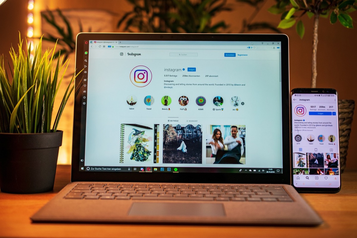 Personne en train de comparer ses statistiques sur ordinateur portable et téléphone, illustration de l'analyse des performances Instagram