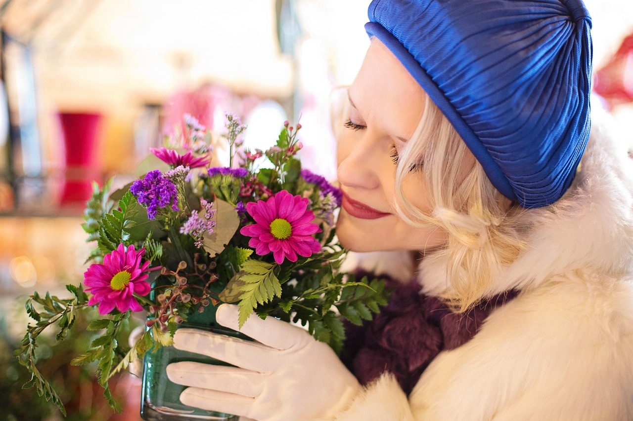 Fleuriste tendant un bouquet à une cliente dans sa boutique