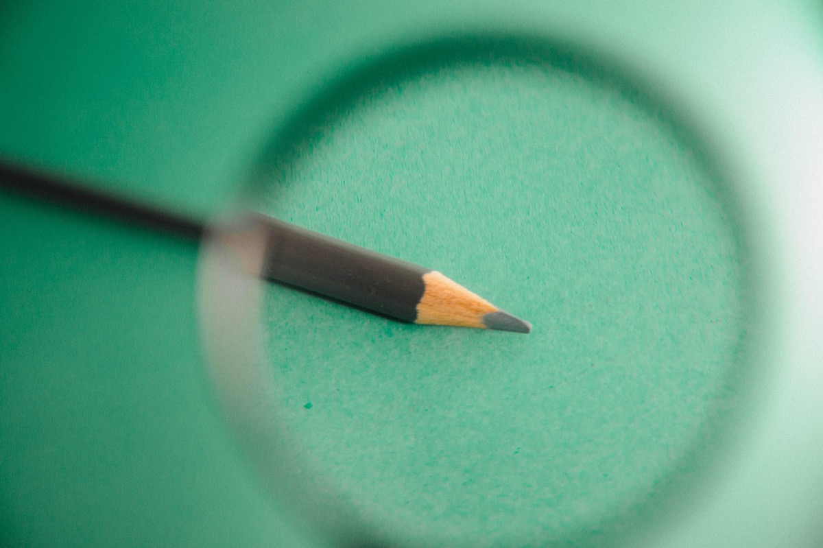 Loupe posée sur un fond sombre, illustration de l'audit et de la vérification du travail d'une agence social media