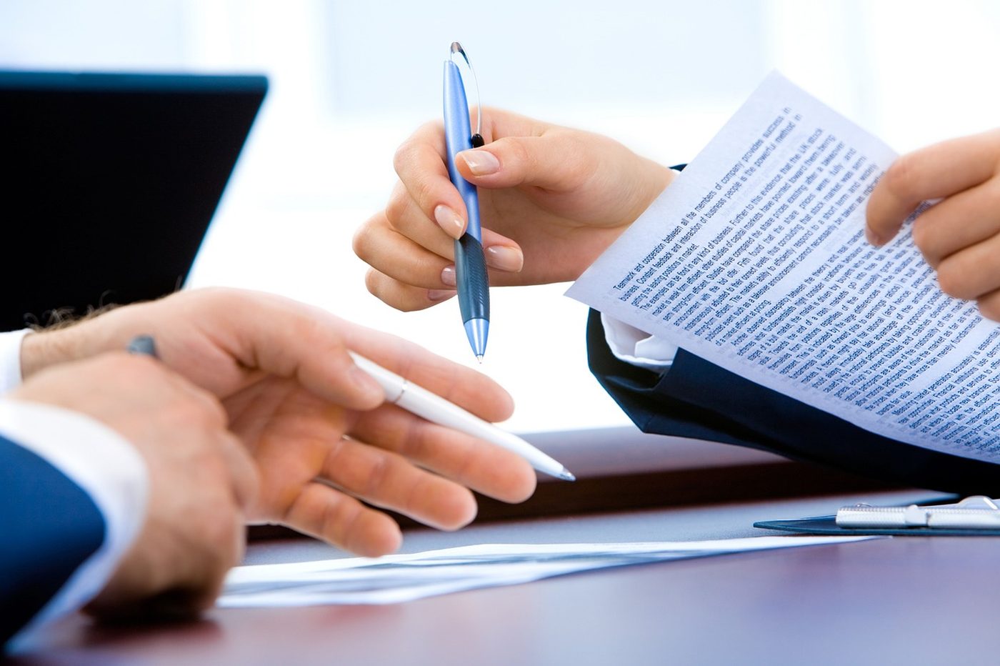 Personne relisant un contrat papier sur un bureau, stylo à la main