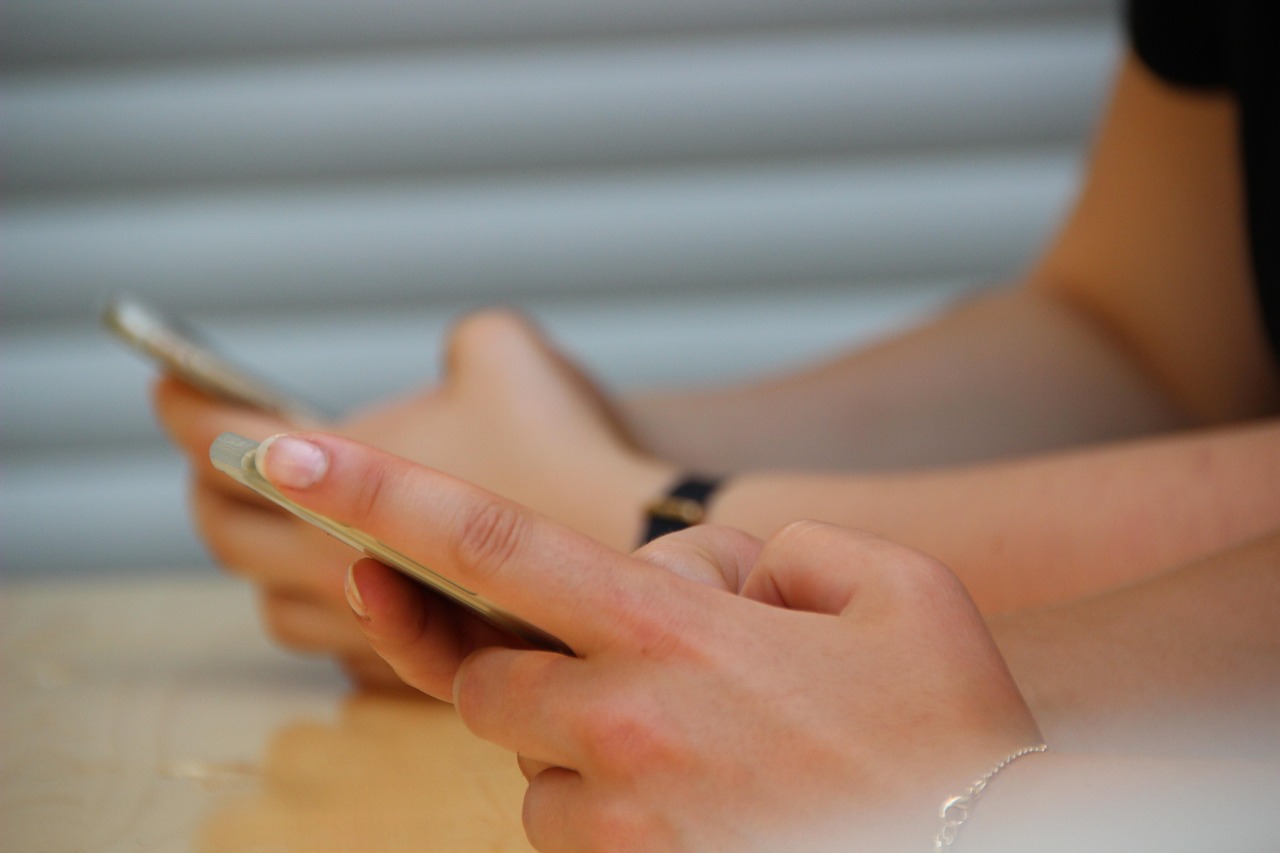 Mains tenant un smartphone ouvert sur les réseaux sociaux, illustration d'un créateur qui retravaille sa stratégie de contenu
