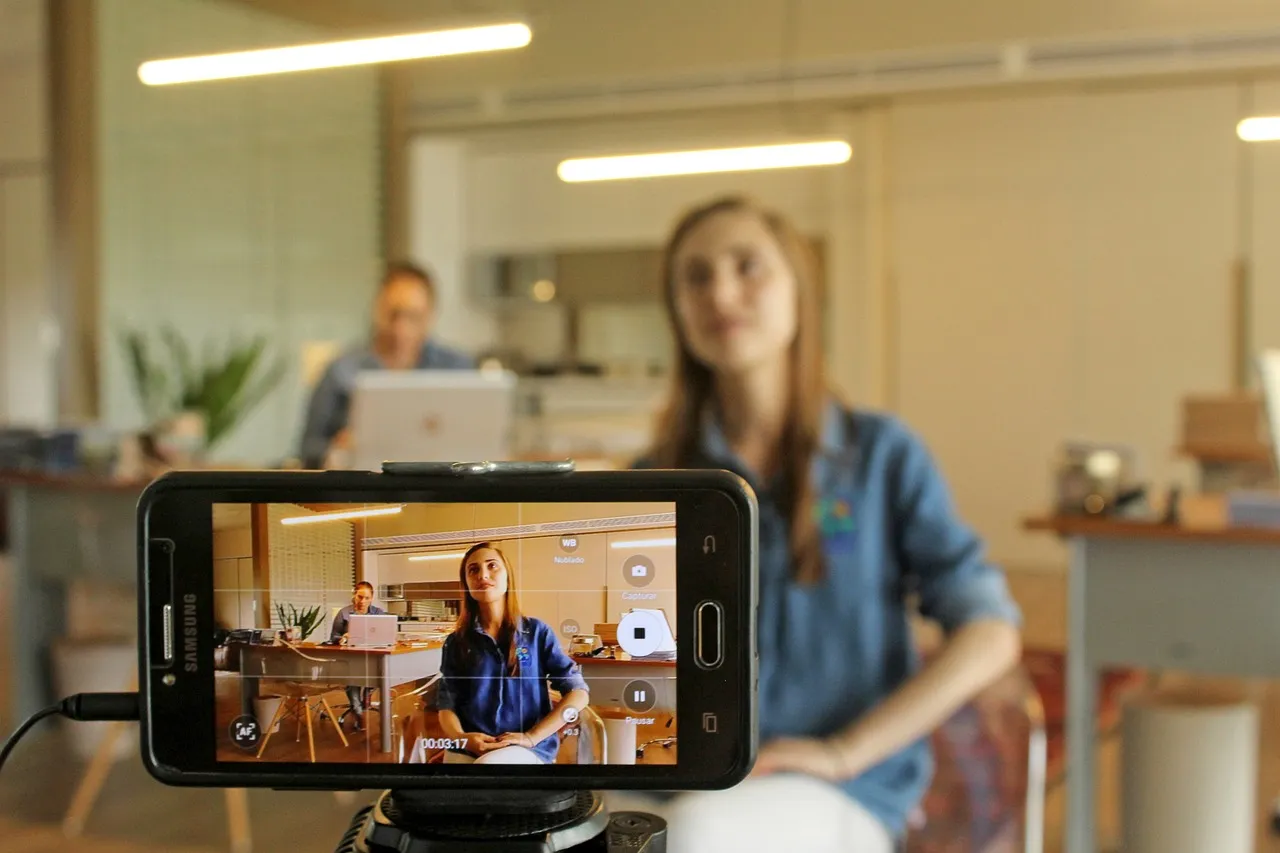 Commerçante en train de filmer une vidéo verticale avec son smartphone pour les réseaux sociaux de son commerce local