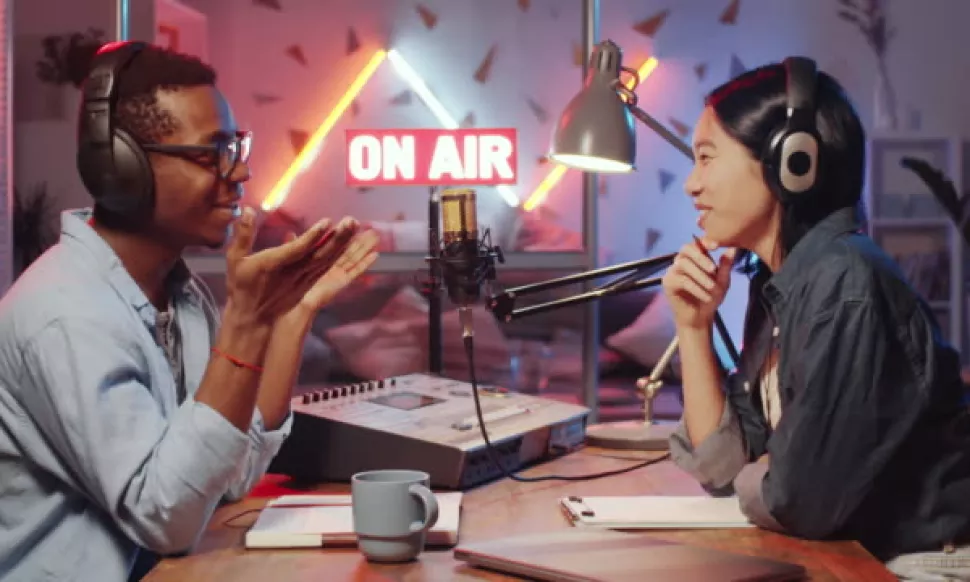 Deux personnes enregistrent un podcast vidéo sous une enseigne ON AIR, casques et micros professionnels