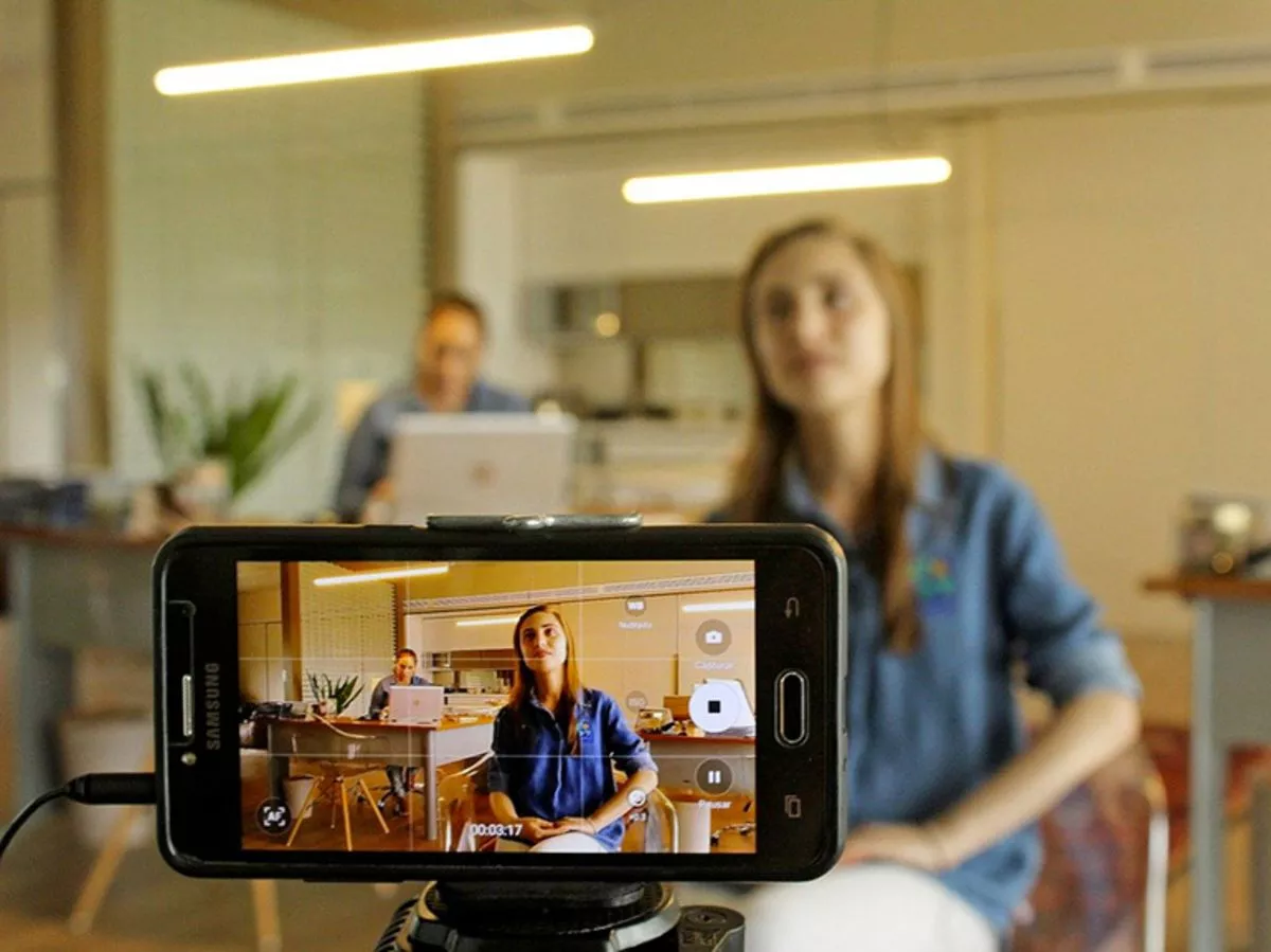 Femme en plein tournage d'une vidéo corporate avec un smartphone sur trépied