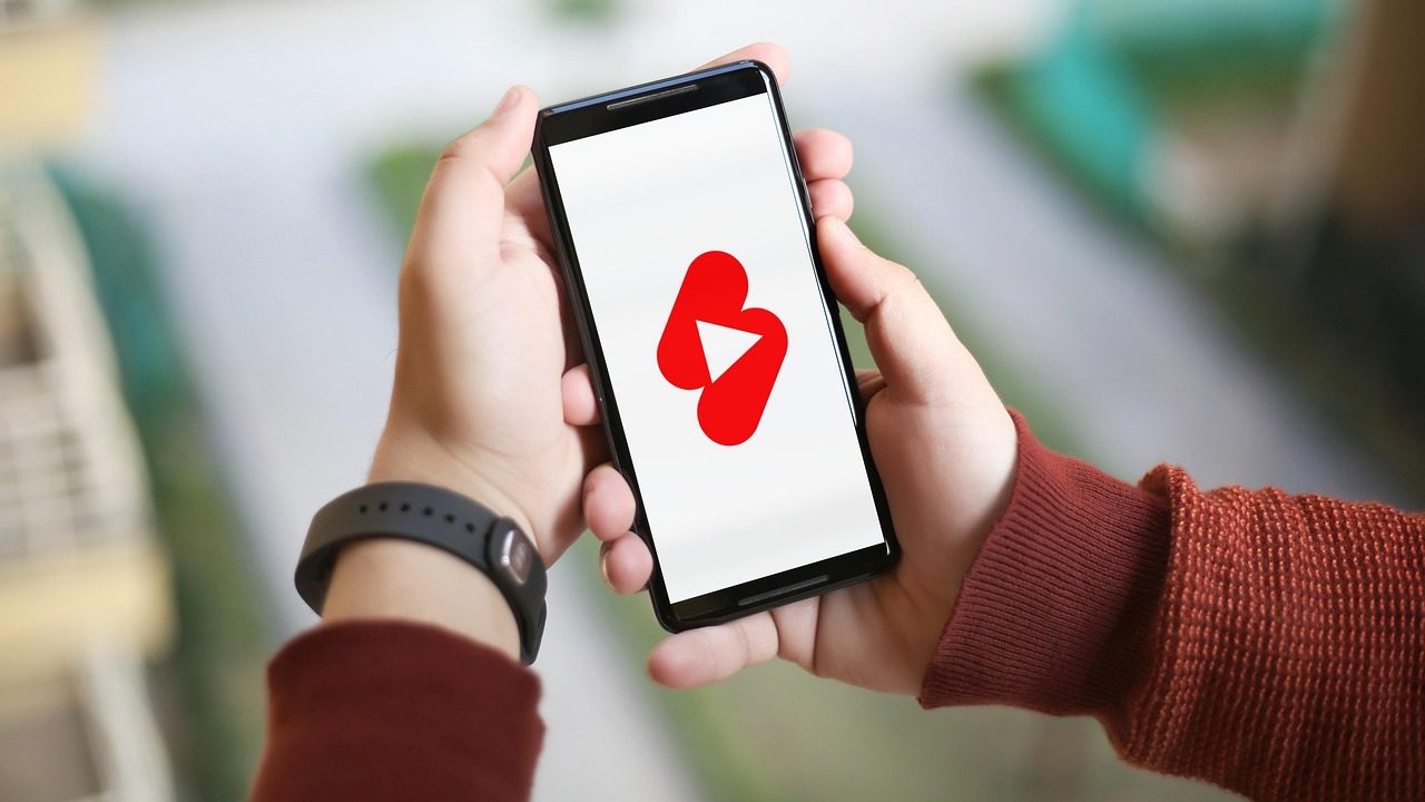 Téléphone tenu à deux mains affichant une vidéo verticale en plein écran
