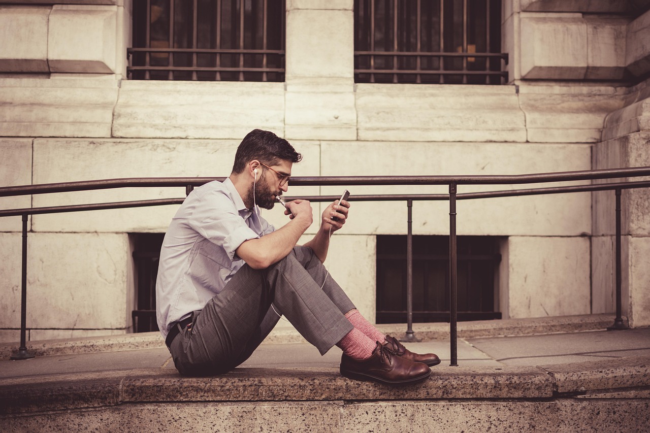Personne assise consultant son téléphone avec des écouteurs, illustration de la reprise en main de sa stratégie de contenu
