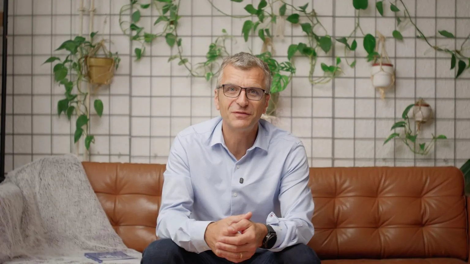 Décor mur végétal, grille métallique et plantes suspendues, canapé cognac