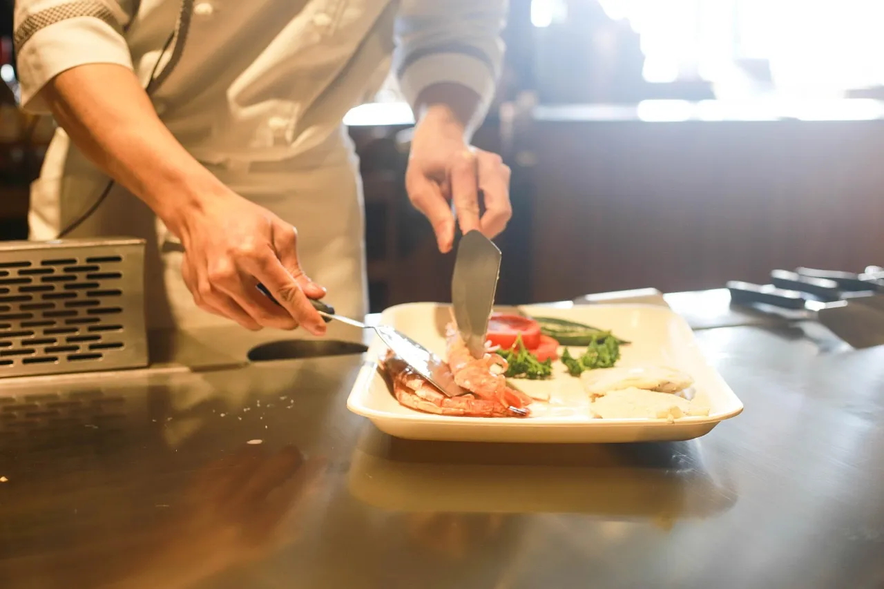 Chef en cuisine professionnelle dressant un plat avec précision, illustration du contenu coulisses authentique qui fait la différence sur les réseaux sociaux d'un restaurant